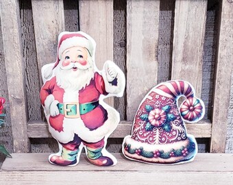 Puede incluir: Un pequeño banco de madera exhibe adornos navideños. Una figura de Papá Noel y un gorro de Papá Noel están en el banco. Un pequeño letrero rosa enmarcado con las palabras "Merry Christmas" está frente al banco.