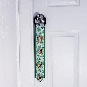 May include: A white door with a green and gold shamrock ribbon with bells hanging from the doorknob.