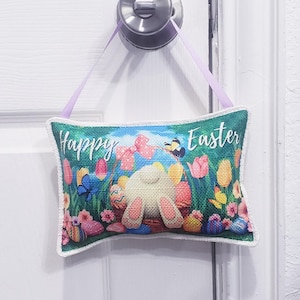 May include: A colorful door hanger with a bunny holding a basket of Easter eggs. The hanger is decorated with flowers, butterflies, and the text "Happy Easter".