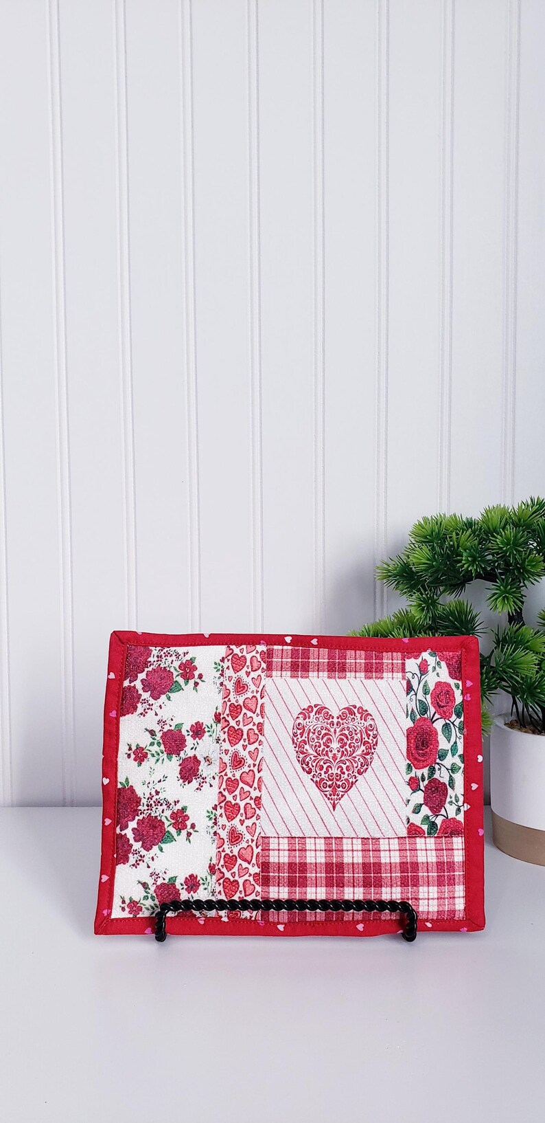 Puede incluir: Un bloque de colcha de retazos rojo, blanco y rosa con un gran coraz&oacute;n rojo en el centro. El coraz&oacute;n tiene un dise&ntilde;o blanco e intrincado. El bloque est&aacute; enmarcado con un borde rojo y tiene peque&ntilde;os corazones rosas en el borde.
