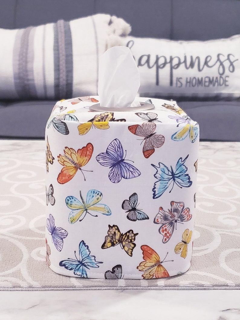 Pu&ograve; includere: Copertura per scatola di fazzoletti di carta bianca con un motivo di farfalle colorate. Il coperchio ha un fazzoletto di carta bianco che sporge dalla parte superiore.