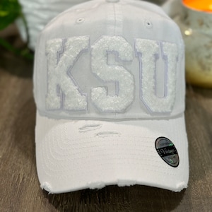One of a kind white distressed hat with letters K S and U  in white