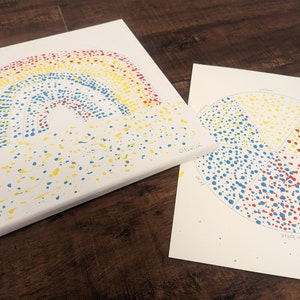 May include: A rainbow painted on a canvas using a dot technique. The rainbow is made of red, orange, yellow, green, blue, indigo, and violet dots. A separate piece of paper shows a circle divided into six sections, each painted with a different color of the rainbow.