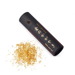 May include: A small black tube with gold lettering that reads "金箔 Kinpaku Edible Gold Leaf" and contains gold leaf flakes. The gold leaf flakes are scattered on a white background.