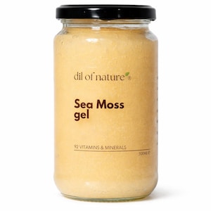 Puede incluir: Un frasco de vidrio transparente lleno de gel de musgo marino de color amarillo claro, con una tapa negra. La etiqueta dice dil of nature, Sea Moss gel, 92 VITAMINS & MINERALS y 500ML. El frasco es cilíndrico y contiene una sustancia espesa.