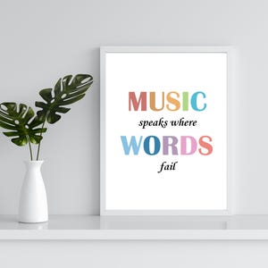 May include: A white framed print with the text "MUSIC speaks where WORDS fail" in colorful letters. The letters are in shades of pink, orange, yellow, green, blue, and purple.