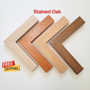 May include: Four wooden picture frames in different shades of stained oak. The frames are arranged in a row, with the lightest shade on the left and the darkest shade on the right. The frames are all the same size and shape, and they have a simple, classic design.