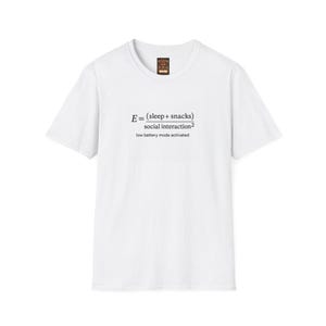 May include: White crew neck t-shirt featuring a printed equation: E = (sleep + snacks) / social interaction², with the text 'low battery mode activated' below. The shirt has a small brown label at the neckline. A casual, humorous design.