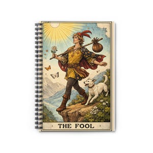 May include: Spiral-bound notebook featuring a tarot card illustration of The Fool. The image depicts a figure with a white dog, walking on a cliff, with a sun and mountains in the background. The figure carries a staff with a rose and a bag. The text "THE FOOL" is at the bottom.