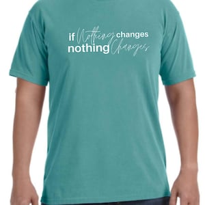 May include: Teal-colored short-sleeve t-shirt with the white text "if nothing changes nothing changes" in a handwritten font. The shirt is a solid color and has a crew neck.