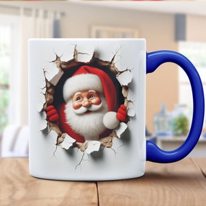 Puede incluir: Taza de cerámica blanca con asa azul. La taza presenta una imagen 3D de Santa Claus asomándose a través de una pared agrietada.
