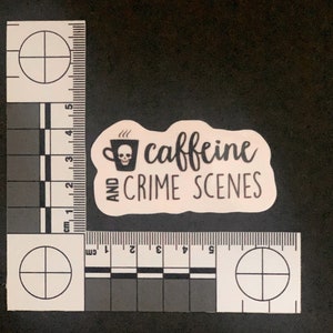 Puede incluir: Una pegatina rosa con texto negro que dice "caffeine and crime scenes". Una ilustraci&oacute;n en blanco y negro de una taza de caf&eacute; con una calavera en su interior est&aacute; por encima del texto.