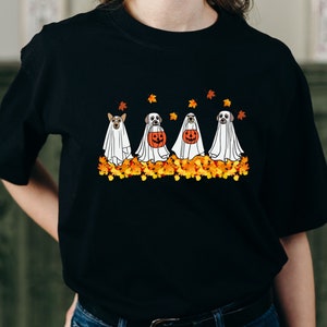 May include: Black t-shirt with a graphic of four dogs dressed as ghosts for Halloween. The dogs are holding pumpkins and are surrounded by autumn leaves.