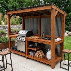 Peut inclure: Une cuisine d'extérieur dotée d'une structure en bois avec un toit et un panneau arrière en métal ondulé. Elle comprend un barbecue à gaz en acier inoxydable, un brûleur latéral, une planche à découper, des étagères, une bouteille de gaz et du bois.