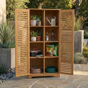 Può includere: Un mobile da giardino in legno con ante a persiana, pieno di forniture per il giardinaggio. I ripiani contengono piante in vaso, attrezzi, sacchi di terra, un annaffiatoio e un tubo flessibile arrotolato. Il mobile è in legno marrone chiaro.