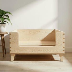 K&ouml;nnte beinhalten: Ein helles Haustierbett aus Holz mit rechteckigem Design. Das Bett hat eine niedrige Vorderseite f&uuml;r einfachen Zugang und wird von vier kurzen Beinen getragen. Die Holzmaserung ist sichtbar, und das Bett steht auf einem Holzboden.