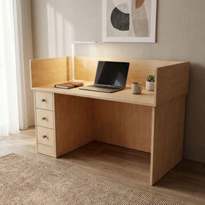 May include: A light wood desk with a built-in hutch and three drawers. A laptop, notebook, mug, and small plant sit on the desk. A white desk lamp is positioned above the laptop. The desk is on a woven rug.