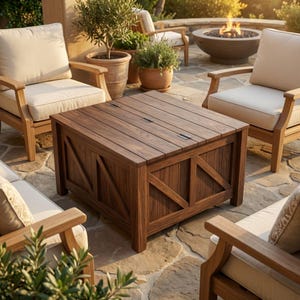 May include: A dark brown wooden outdoor storage table with a slatted top and decorative X-shaped accents on the sides. The table is surrounded by wooden chairs with cream-colored cushions, creating a cozy outdoor seating area.