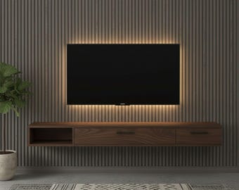 May include: A modern entertainment center with a dark wood floating cabinet, a large black television, and a warm light strip. The wall behind the TV has vertical wood paneling. A potted plant and patterned rug complete the room.
