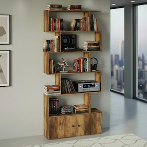 May include: A wooden bookshelf with a unique, zig-zag design. The shelves are filled with books, a record player, and decorative items. The bottom section features a cabinet with two doors. The bookshelf is against a light gray wall, with a city view visible through a window.