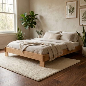 May include: A light-colored wooden bed frame with a matching headboard and footboard. The bed is made up with light-colored bedding, including pillows and a blanket. A cream-colored rug sits on the floor in front of the bed.