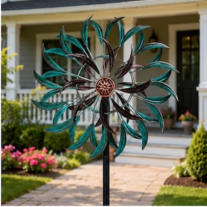 May include: A metal wind spinner featuring two circular tiers of curved, leaf-shaped blades in a teal patina finish. The center is accented with a copper-colored floral medallion. The entire structure is mounted on a tall, thin black metal pole.