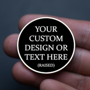 May include: A black round coin with white text that reads "YOUR CUSTOM DESIGN OR TEXT HERE (RAISED)".