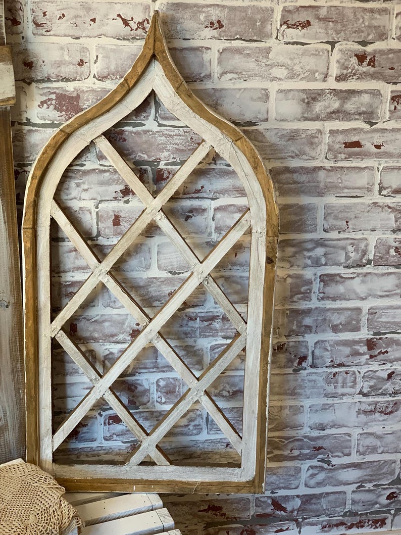Puede incluir: Un marco de ventana decorativo de madera con un dise&ntilde;o de celos&iacute;a de diamantes. El marco tiene un acabado blanquecino desgastado con un borde de madera natural. El marco est&aacute; montado contra una pared de ladrillo envejecido.