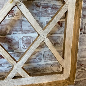 Puede incluir: Un elemento decorativo de pared de madera r&uacute;stica con un dise&ntilde;o de celos&iacute;a de diamantes. El marco es de madera natural con un acabado blanco envejecido. El fondo es una pared de ladrillo con pintura roja y blanca.