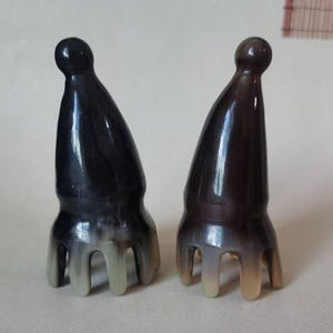 以下が含まれることがあります： 黒と茶色の、角の形をした装飾品が2つ。どちらも丸みを帯びた上部と、3つの湾曲した爪が付いたベースがあります。これらのオブジェクトは、装飾用またはユニークなアクセサリーとして使用される可能性があります。