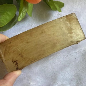 Op de afbeelding: Een lichtbruin, rechthoekig, glad en licht gebogen stuk hout. Het hout heeft een natuurlijke, licht getextureerde oppervlak.