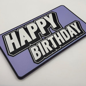 Op de afbeelding: Een rechthoekig, lavendelkleurig bord met de woorden "HAPPY BIRTHDAY" in vette, witte, omlijnde letters. De tekst staat in een zwarte rand en het bord heeft afgeronde hoeken.