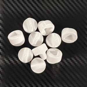 May include: A set of ten white plastic game pieces with different symbols on each side. The symbols include a triangle, a square, a circle, and a line.