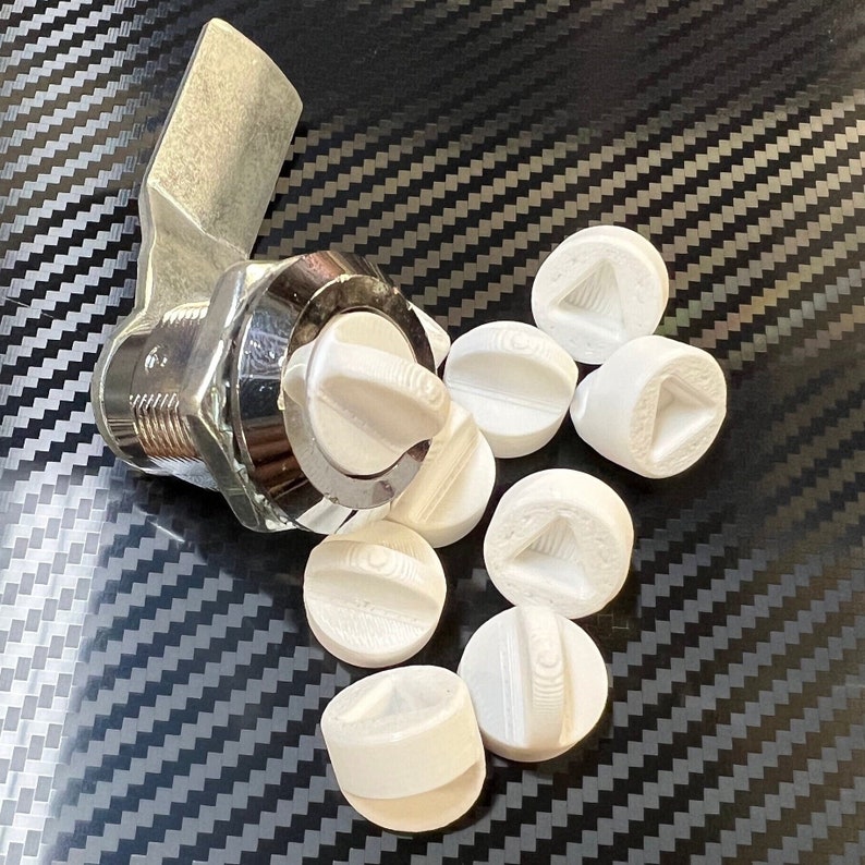 May include: A silver metal door knob with a white plastic handle and eight white plastic key covers. The key covers have a variety of geometric shapes.