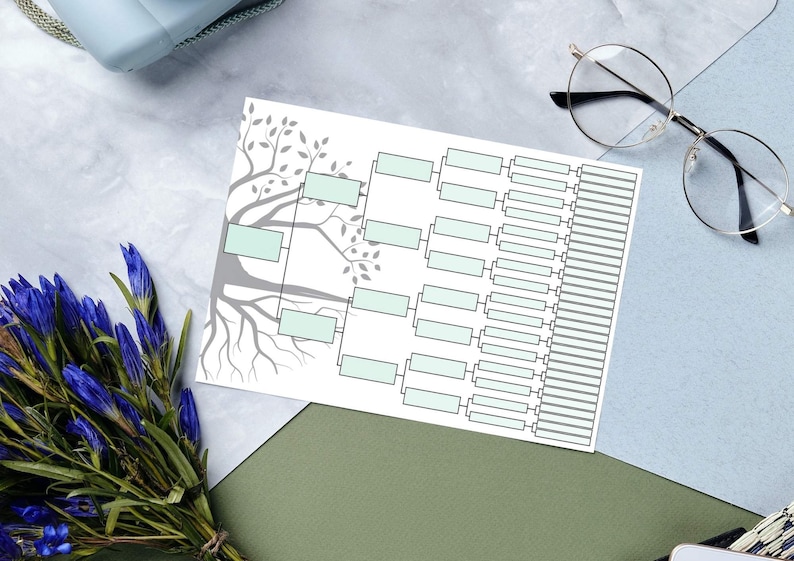 K&ouml;nnte beinhalten: Ein druckbarer Stammbaum mit einer grauen Baumillustration und leeren Feldern f&uuml;r Namen. Der Stammbaum liegt auf einer grauen Oberfl&auml;che mit einem Strau&szlig; blauer Blumen und einer Brille.