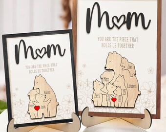 May include: Two wooden signs with the word "Mom" and a heart. The signs feature a bear family with the names of each family member. The text on the signs reads "You are the piece that holds us together."