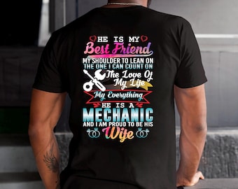 Puede incluir: Camiseta negra con un diseño gráfico en la espalda. El diseño incluye el texto "HE IS MY Best Friend", "HE IS A MECHANIC" y "Wife". El diseño también presenta una llave inglesa y otros elementos decorativos.