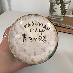May include: A white ceramic vase with a green glaze and a handwritten inscription that reads "VESUVIAN ITALY # 34 92".