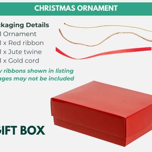 May include: A red gift box with the text "GIFT BOX" and "CHRISTMAS ORNAMENT". The image also shows a red ribbon, jute twine, and gold cord. The packaging details include 1 ornament.