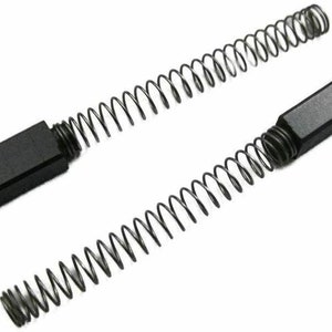May include: Two black carbon brushes with metal spring attachments. The brushes are rectangular and have a flat surface. The springs are coiled and are attached to the brushes.