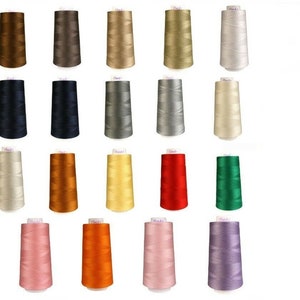 May include: A collection of sewing thread spools in various colors, including brown, navy, gray, beige, orange, red, and pink. The spools are arranged in rows, showcasing a range of hues suitable for various crafting projects.