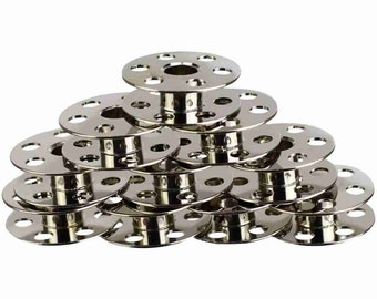 May include: A stack of 12 silver metal bobbins for sewing machines.