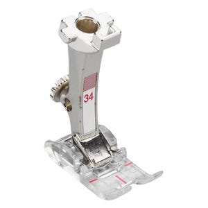 May include: A silver sewing machine presser foot with a clear plastic base. The foot has a label with the number 34 and red stripes. The top has a square opening.