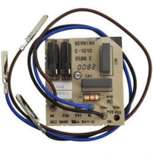 May include: A close-up of a circuit board with wires and components. The board has the text "BERNINA E-1010 0586 E 0082" printed on it.