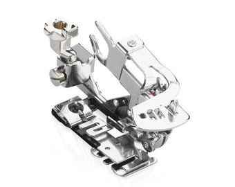 May include: A silver sewing machine foot attachment with a metal screw and a small metal lever. The foot is designed for sewing rolled hems.