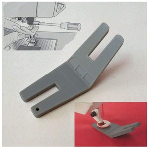 May include: Gray plastic sewing machine foot with a wide opening and a small hole on the side. The foot is designed to help sew around corners and curves.