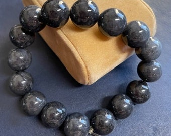 May include: A black beaded bracelet with a total of 12 beads. The beads are round and have a slightly textured surface.