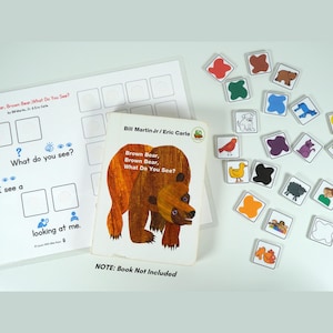 Op de afbeelding: Educatieve set met een boek getiteld "Brown Bear, Brown Bear, What Do You See?" van Bill Martin Jr. en Eric Carle, en bijpassende tegels met afbeeldingen. De boekomslag toont een bruine berenillustratie. Een werkblad met in te vullen vakken is ook inbegrepen.