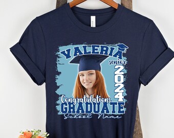 May include: Navy blue t-shirt with a blue and white graphic design featuring a graduate wearing a cap and gown. The graphic also includes the text "VALERIA senior 2024 Congratulations GRADUATE School Name".