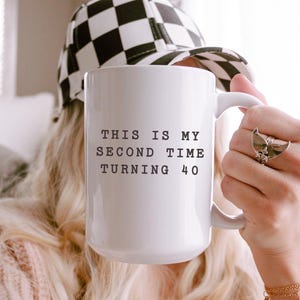 May include: White ceramic mug with black text that reads "This is my second time turning 40".